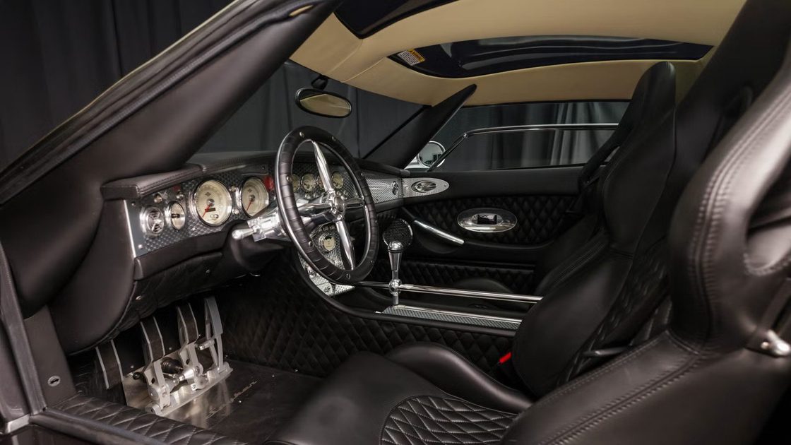 vehicle interior view black leather quilted seats analog gauges polished metal shifter minimalist cockpit design.
