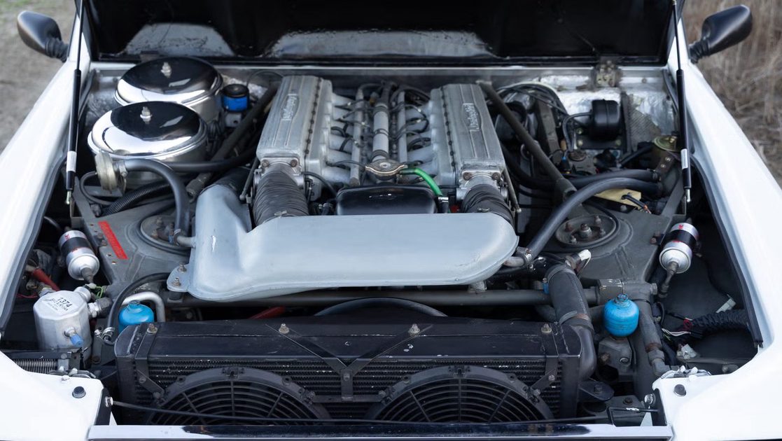front view of engine bay with exposed engine components, intake manifold, radiator.