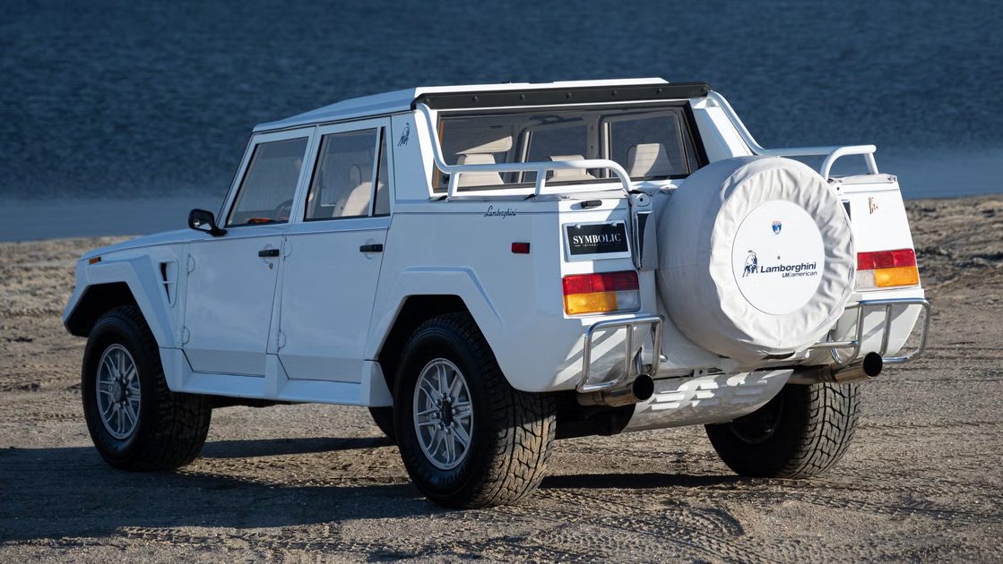 rear three quarter view of white off road suv with rear spare tire parked beside waterfront.