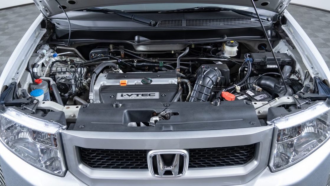 front view of engine bay with visible intake cover, battery, hoses, radiator support.